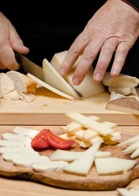 Close up chef cutting cheese on wooden board
